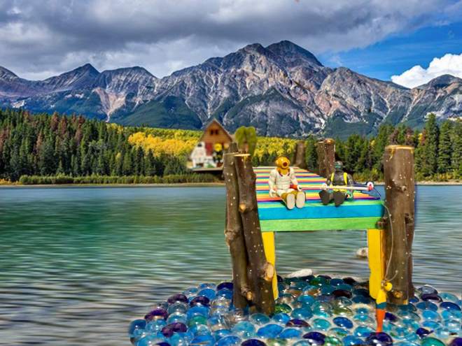 Toys sitting on a dock of a lake talking and fishing
