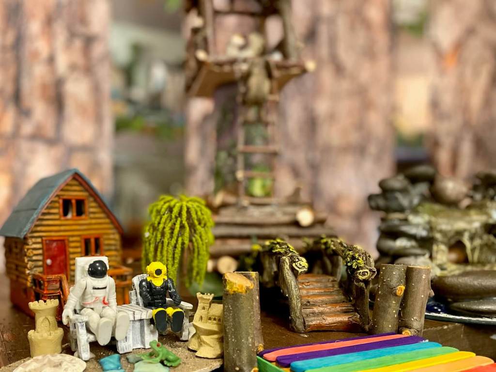 Toys sitting and talking at a lake in front of a cabin 