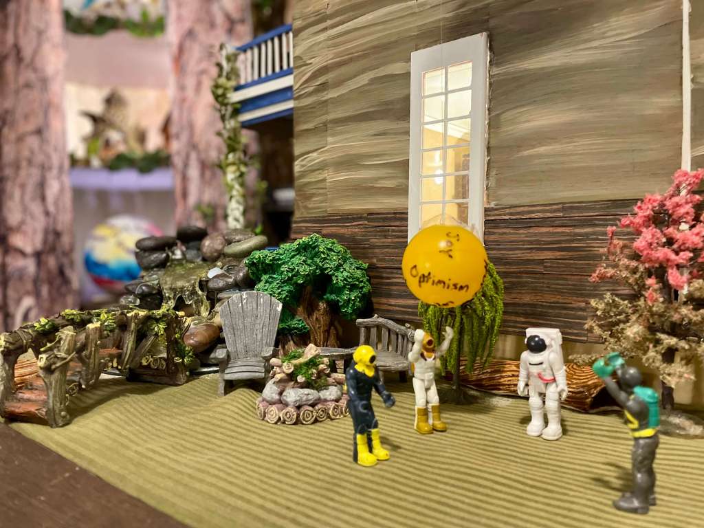 Small toys throwing a beach ball with emotion words written in the ball