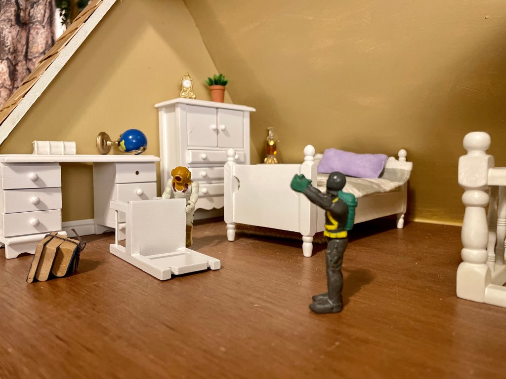 One small toy is knocking over some items in their room while another toy has their hands in the air