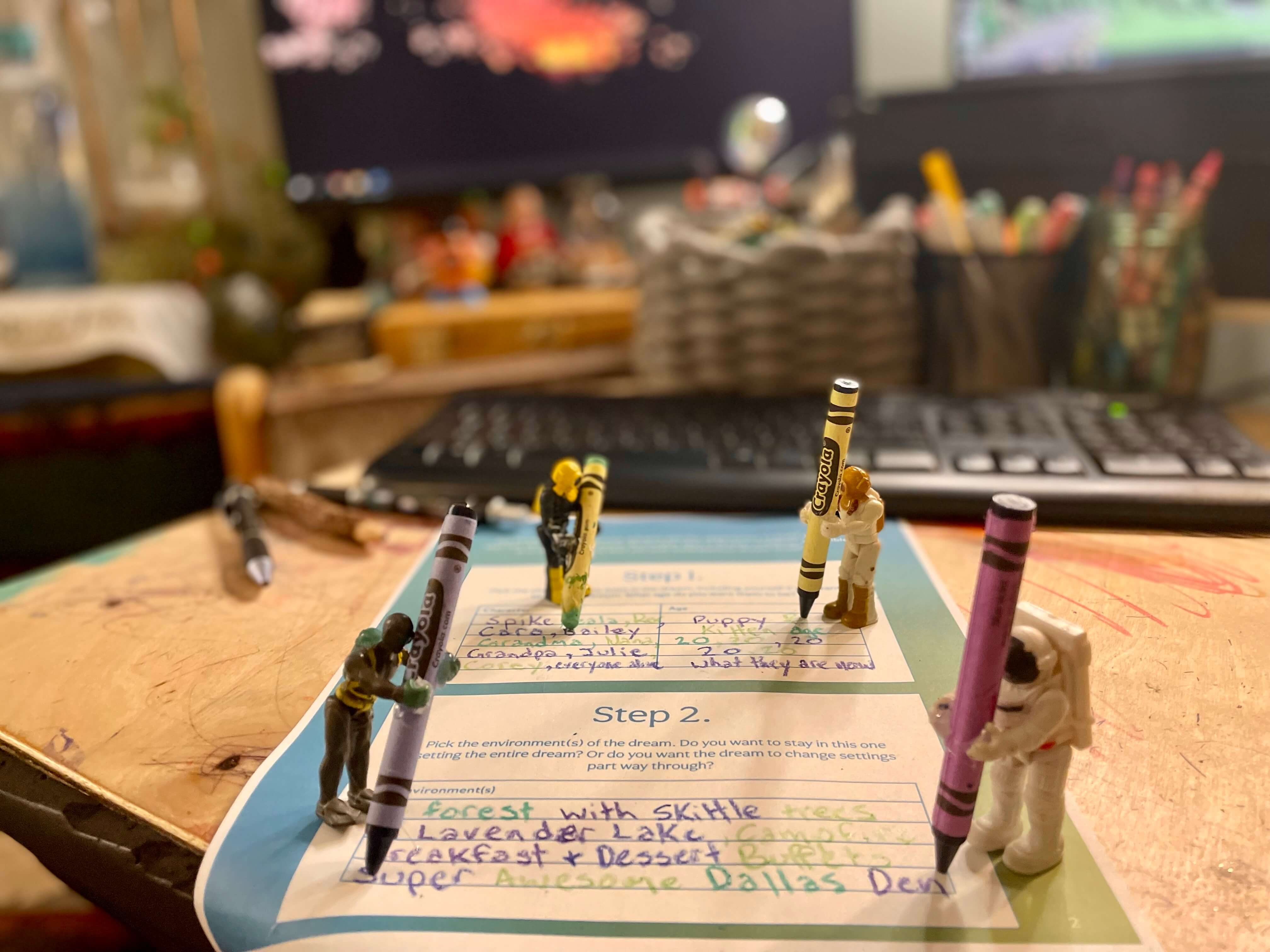4 miniature toys with crayons in their hands filling out the Grief Dreams: Dream Builder Worksheet together on an office table