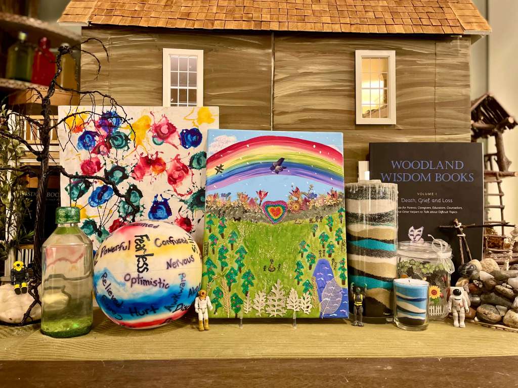 4 standing in front of expressive activities such as Feelings Tornadoes, the Beach Ball of Emotions, and Layers of Love