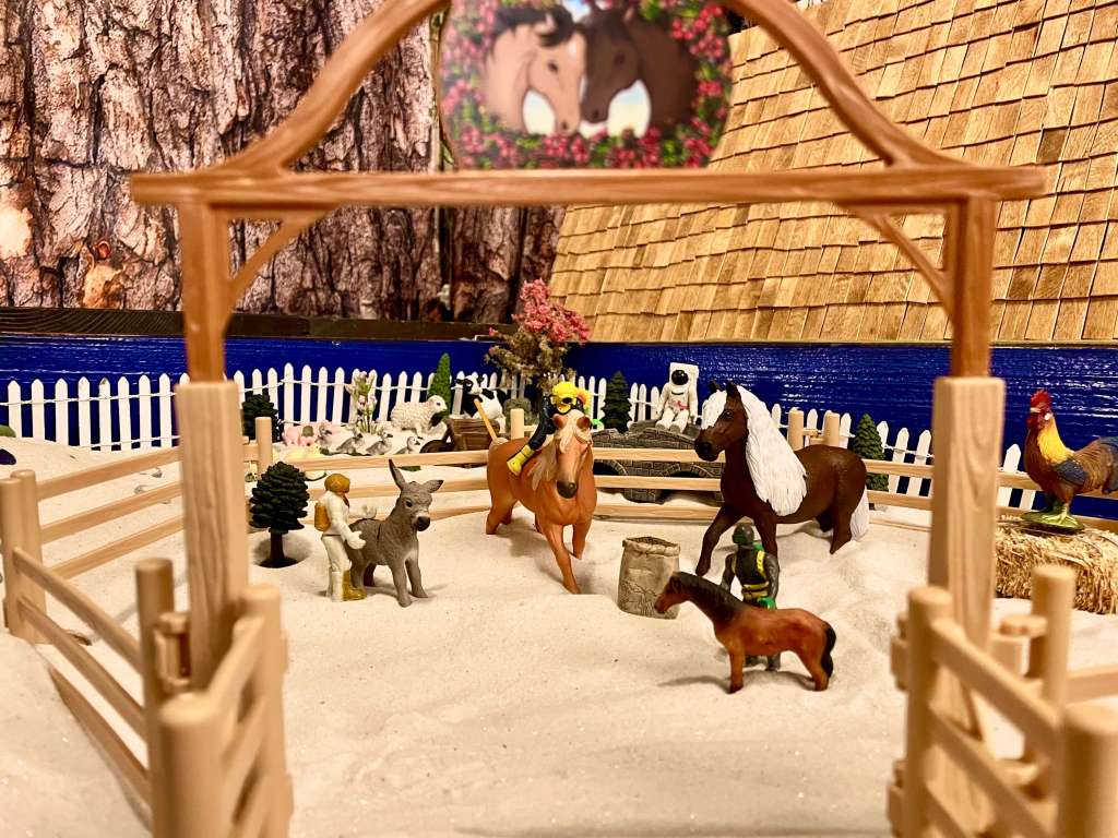 4 toys at a grief horse camp with 3 horses, a donkey, pigs, a rooster, a cow, a sheep, a hay bale, and a wheelbarrow 