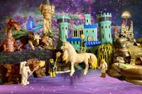 4 toys holding magic wands with a unicorn, dragons, castles, willow tree, and a wishing well